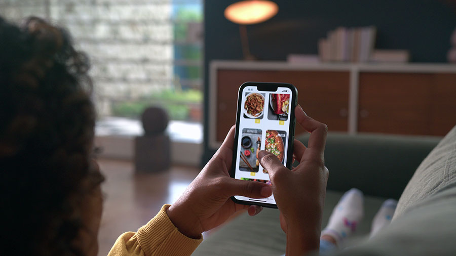 Hand closeup browsing food online store on cellphone app. Person scrolling screen choosing meal on menu