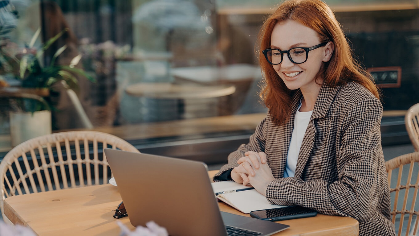 A business woman sitting at a desk with a laptop reading about what's new in QuickBooks Online.