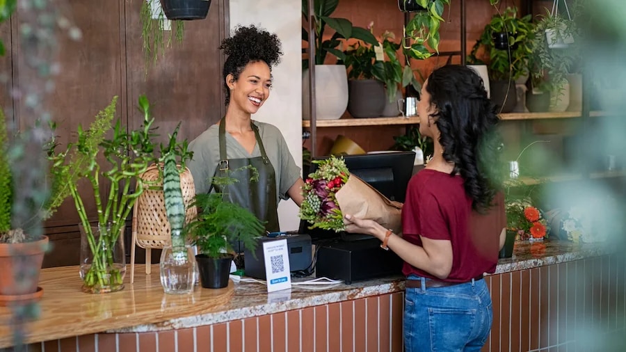 Flower shop owner and customer talking and smiling.