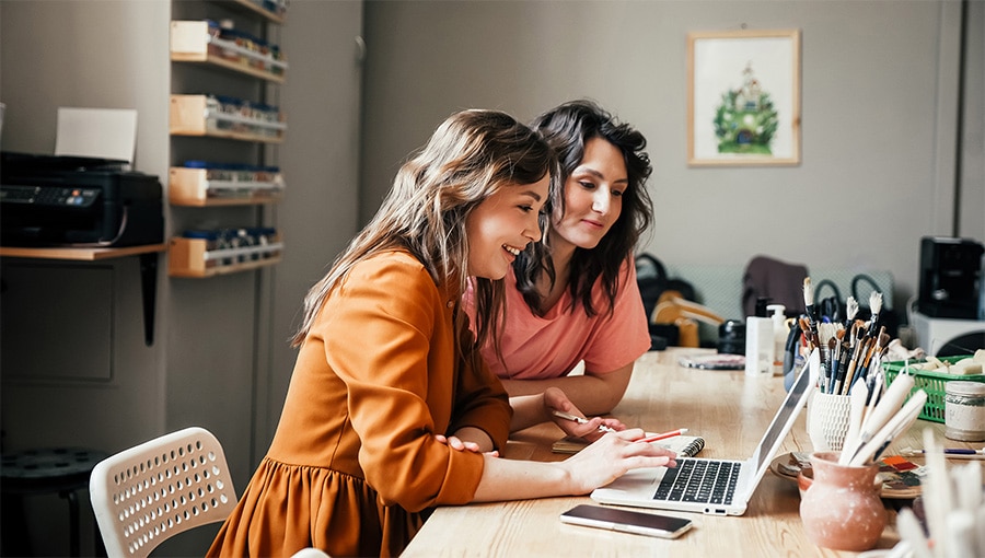 Two people sitting at a table with a laptop.