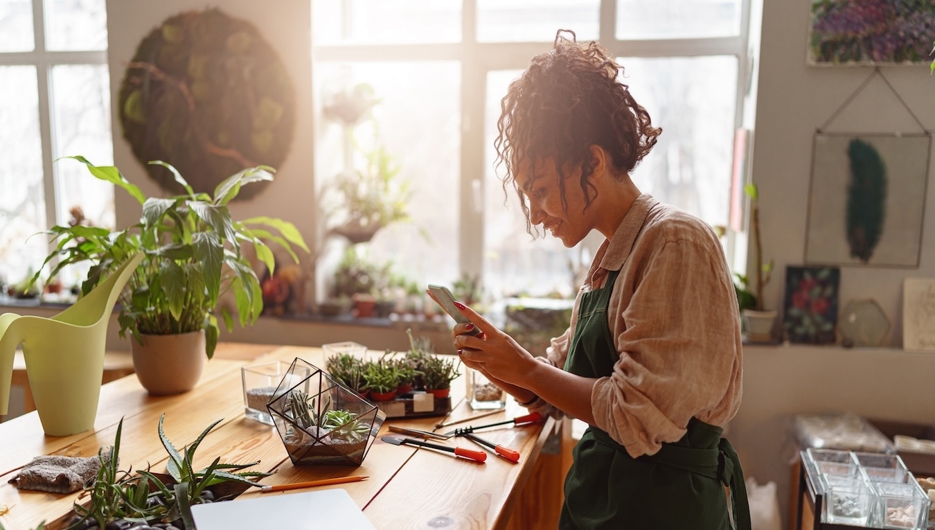 A small business owner in a plant shop taking photos of products 