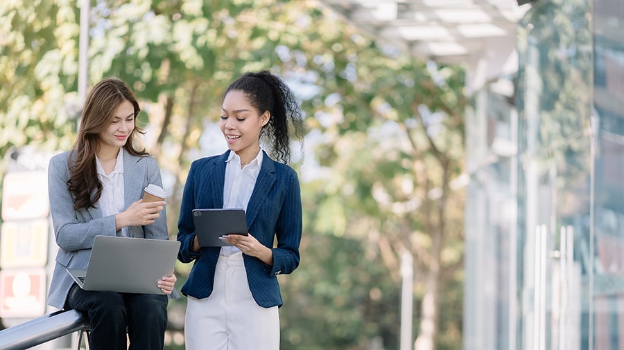 Two accountants discuss what's new in QuickBooks in front of a building.