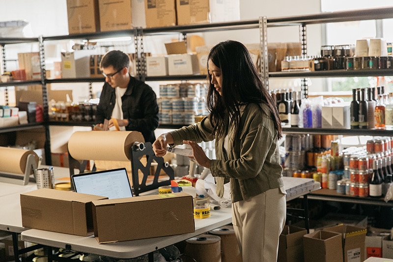 Two young employees prepare packing and shipping supplies at a small business