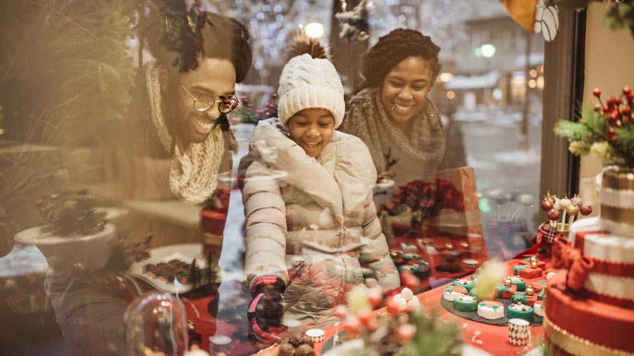 a family of three looking into a holiday window display