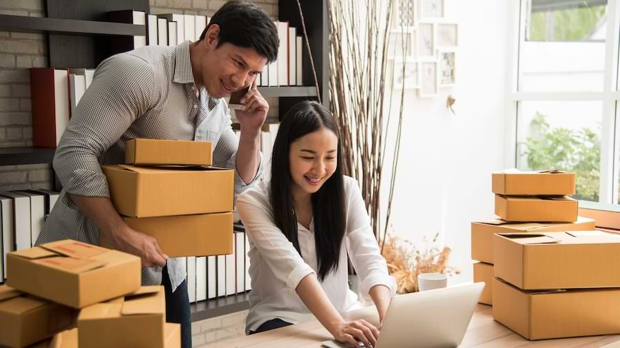 Two business owners using a phone and a laptop to put orders in.