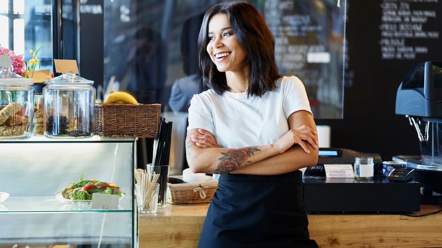 Cafe worker stands behind counter with tattoo