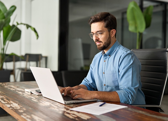 A person sitting at a desk with a laptop computer reading about Intuit Assist.