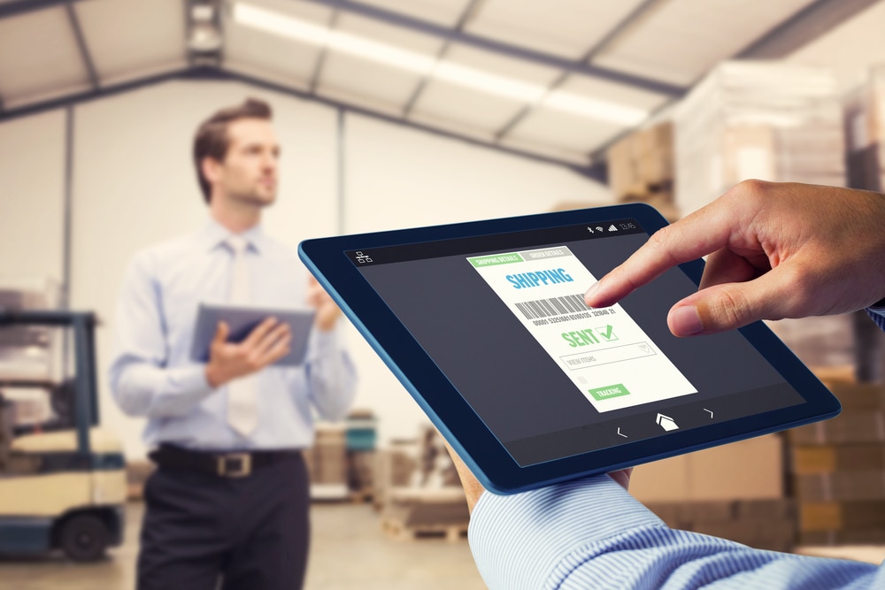 Two men standing in a warehouse using tablets to view order details.
