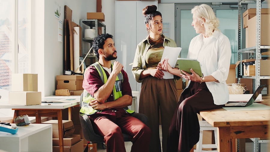 3 people in a meeting in a small, modern warehouse office.