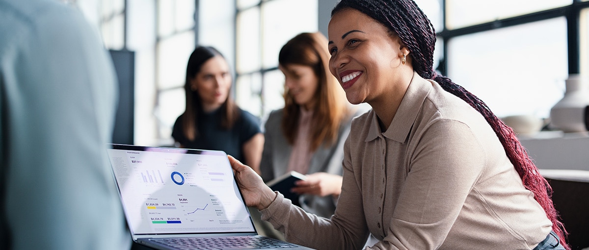 A smiling professional woman holds a laptop and demonstrates predictive analysis.