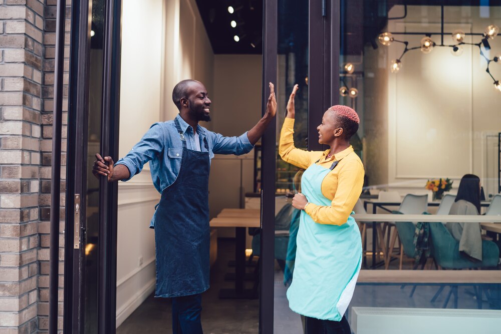 Business partners high-five in celebration at their retail location.