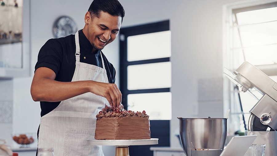 A person in a chef's hat is holding a cake.
