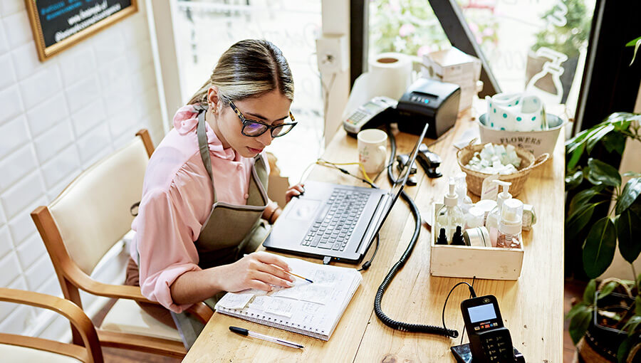 A person sitting at a desk with a laptop and a cup of coffee.