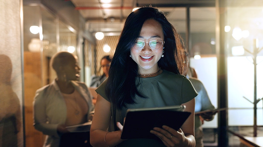 A small business owner smiles as she uses artificial intelligence on her tablet.