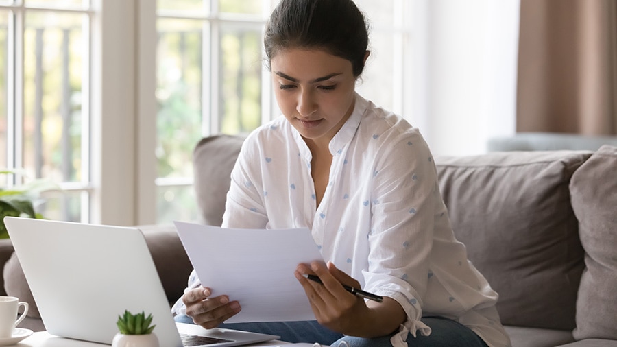 A person reading about stale-dated checks at her home on a couch.