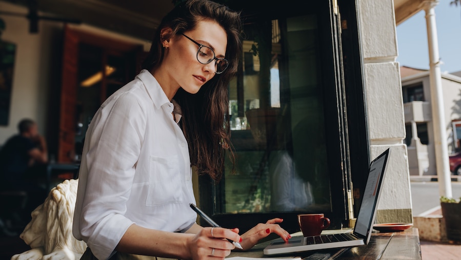 Pigiste prenant des notes et utilisant son ordinateur portable.