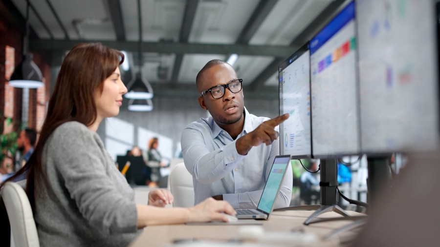 Colleagues analyzing data on multiple monitors.