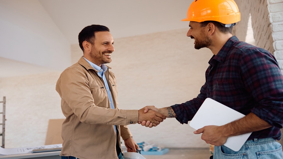 Two people shaking hands over a wooden table.