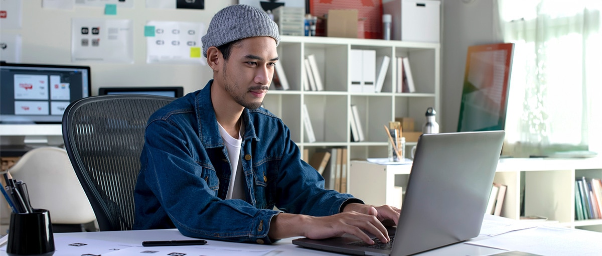 A young man sits at a laptop computer.