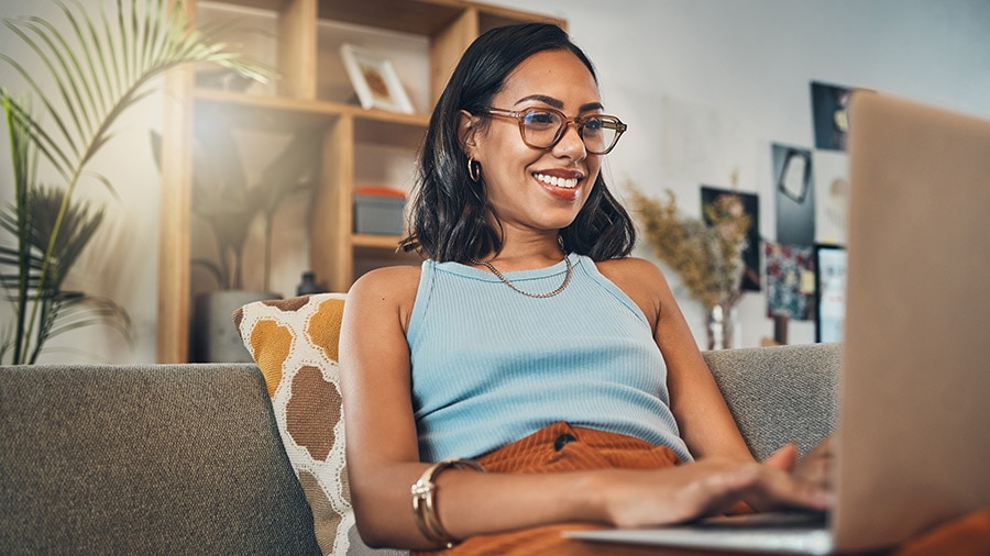 A person sitting on a couch with a laptop, reading about Intuit Assist for QuickBooks.