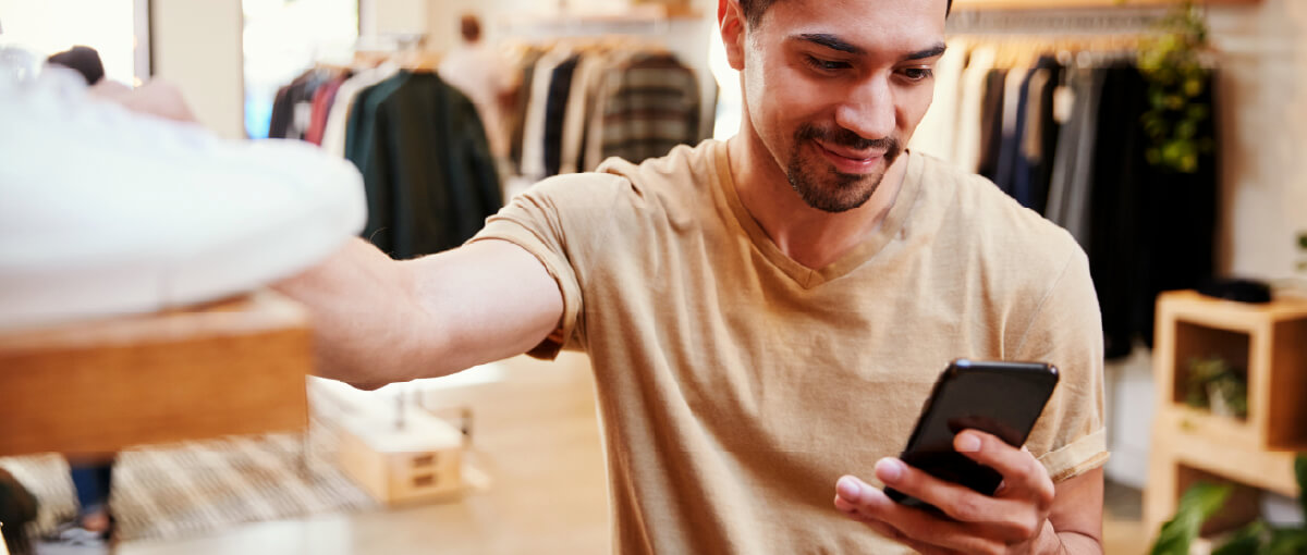 A man holding a cell phone in a clothing store