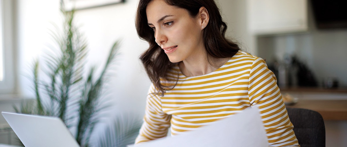 A person looking at a laptop and sheet of paper reading about SUTA tax.