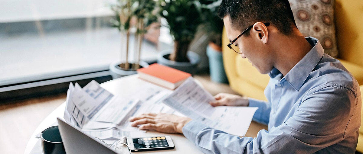 An man pays bills in his home office