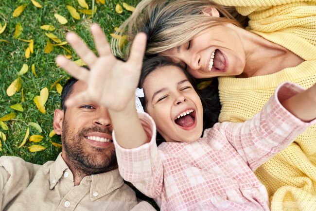 A person and two children smiling and holding hands.