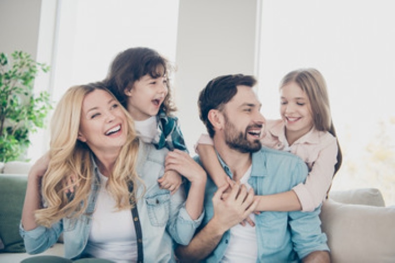 A family is smiling while sitting in a room.