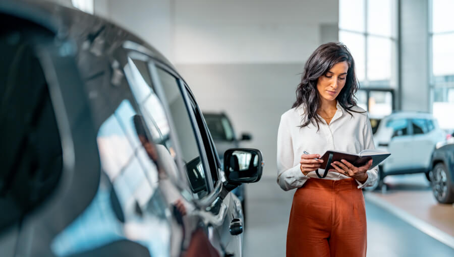An image of a woman practicing direct sales by selling a car at a dealership.