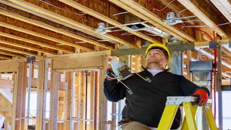 A person fixing a ceiling fan in a garage.
