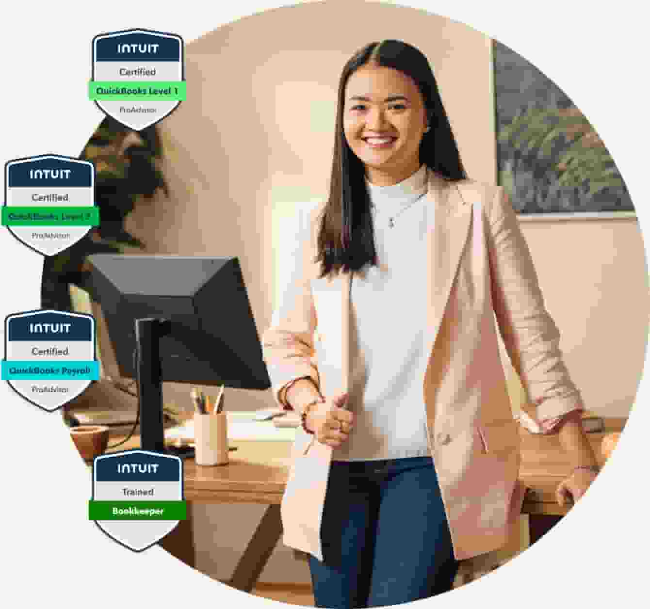 A confident and. proud female QuickBooks accountant standing at desk smiling with certification badges visible