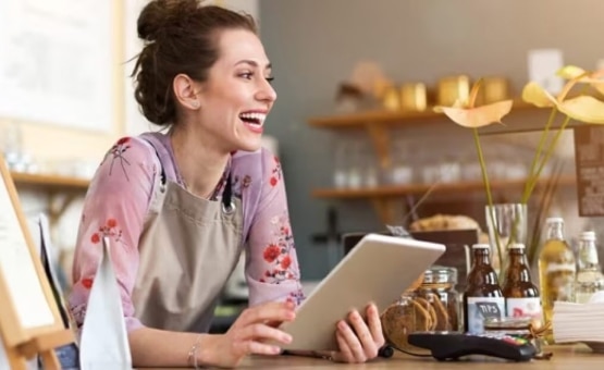 A photo of a woman smiling and holding a tablet.