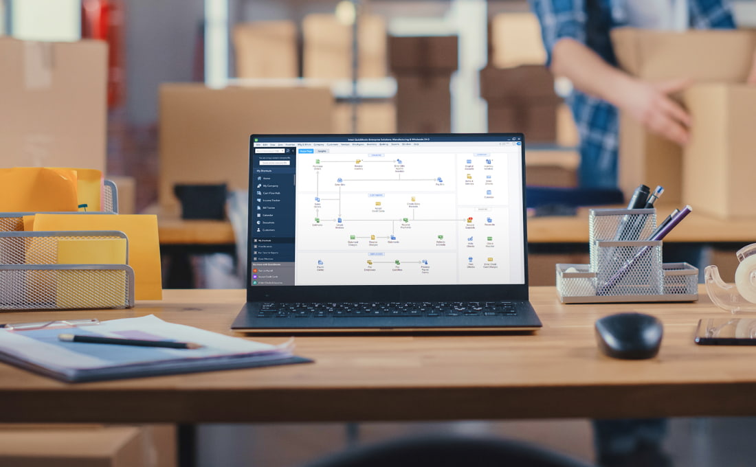 Laptop on a desk with QuickBooks Enterprise visible on screen