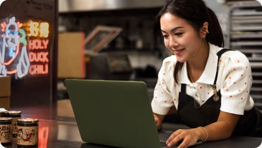 QuickBooks Online customer and small business owner working on a laptop computer within her manufacturing retail workspace