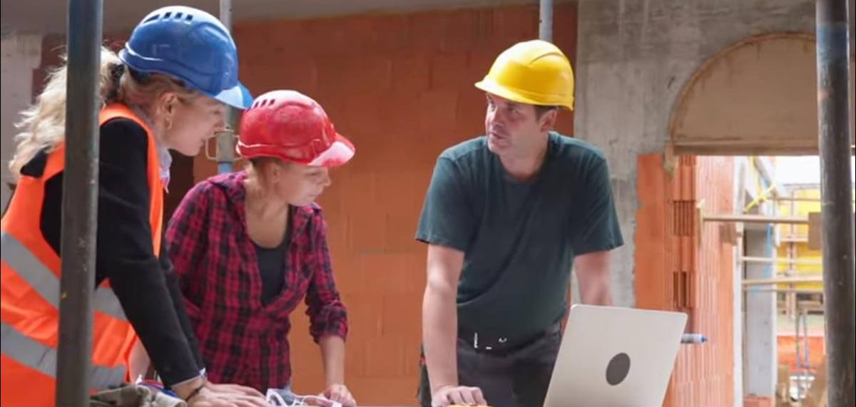 People wearing hard hats and working on a laptop.