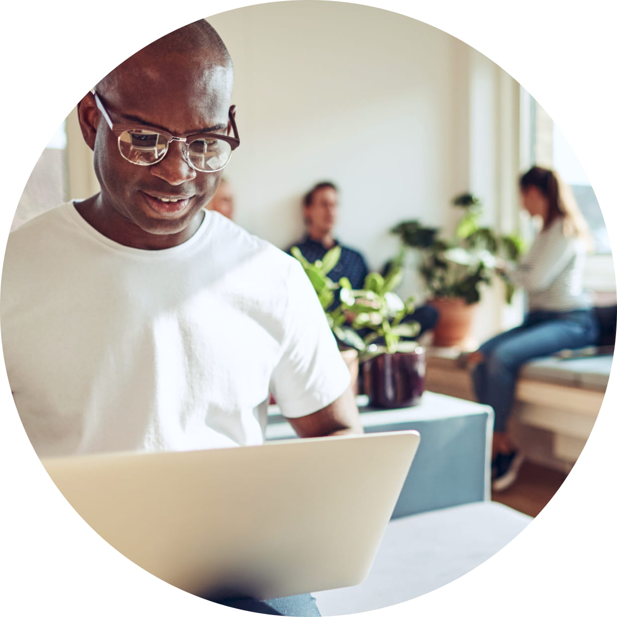 Business owner working on laptop with employees in background