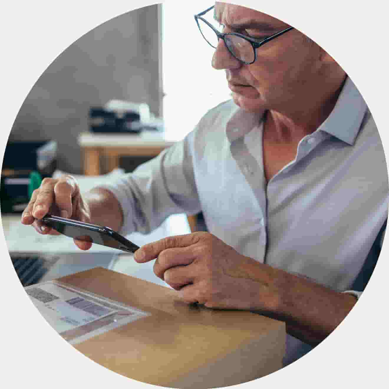 Man working on laptop scanning inventory on mobile device