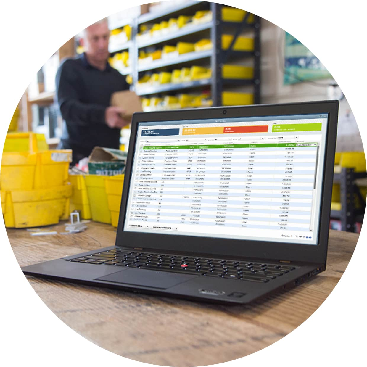 Man in warehouse looking through inventory with laptop