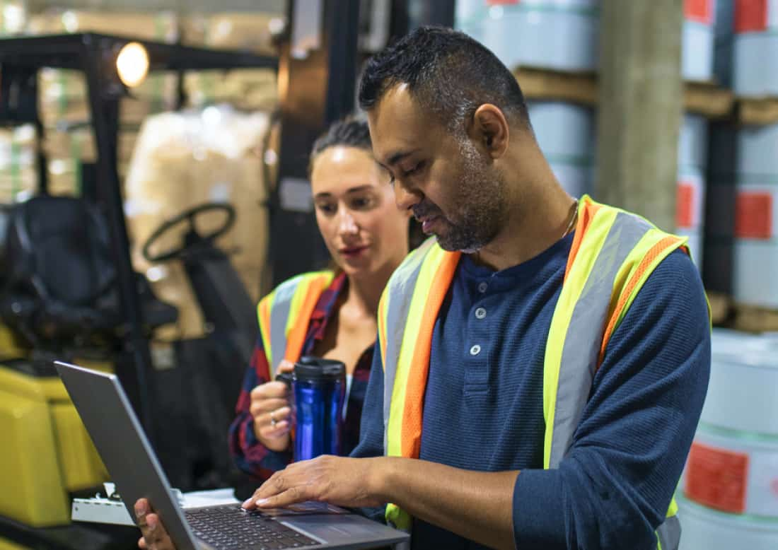 Man and woman working on laptop in warehouse using QuickBooks Enterprise wholesale distribution edition software