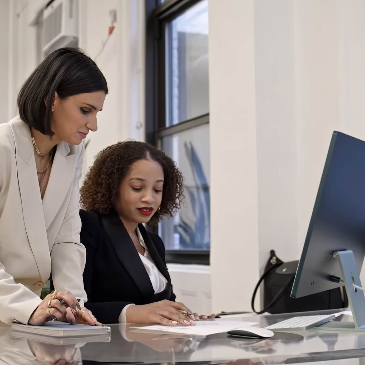 two person sitting at a desk with a computer.