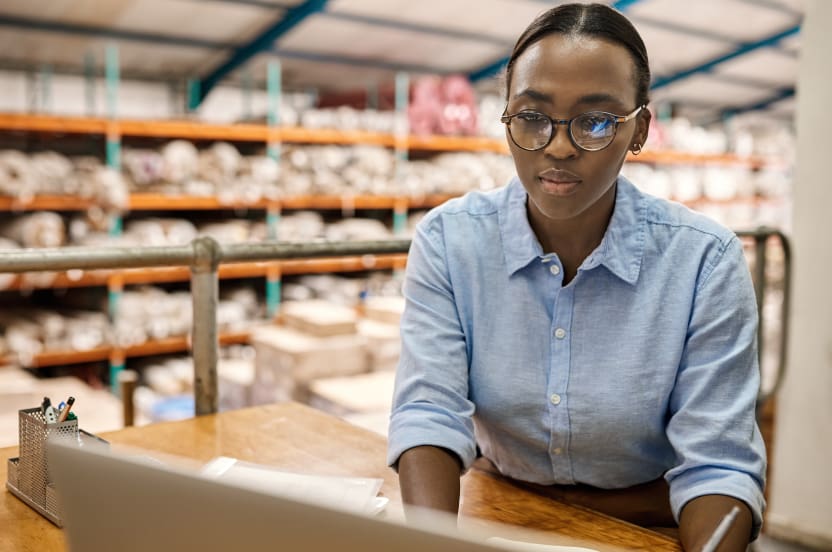 Woman working on laptop in inventory warehouse