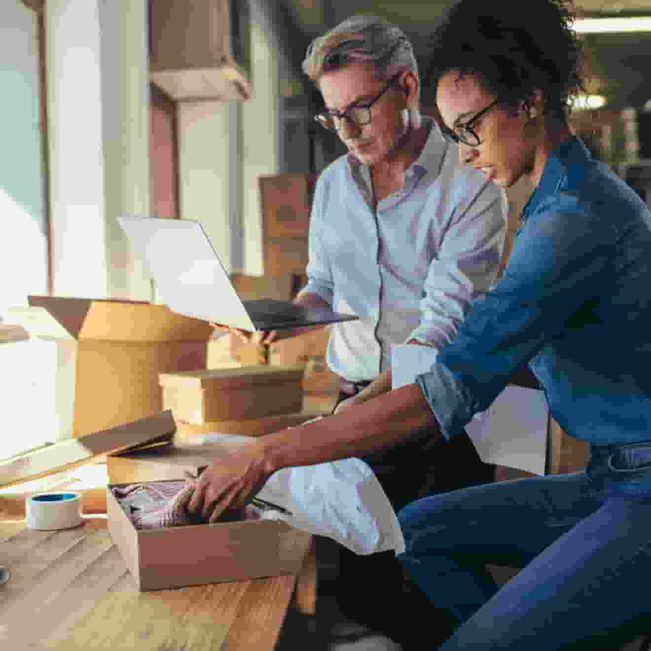 Woman and man working on inventory with a laptop computer in a warehouse