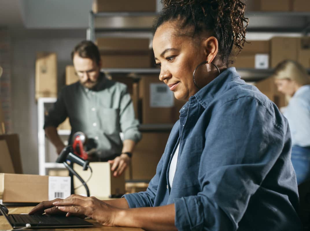 Woman working on laptop with employees in background