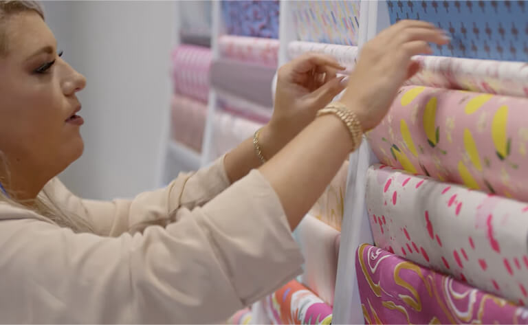 A business owner is working on a display of colorful fabrics.
