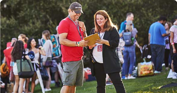 Man and woman at a sporting event looking at a clipboard