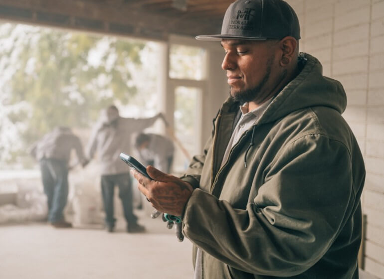 Contractor on job site entering info into an app on his mobile device