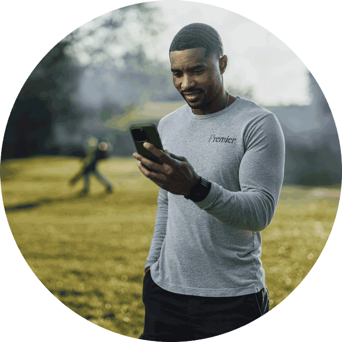 Landscaper using a phone to keep track of business while on-site at a field.