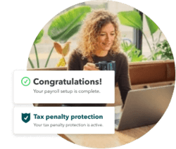 Female employer using a laptop to run payroll with active tax penalty protection.