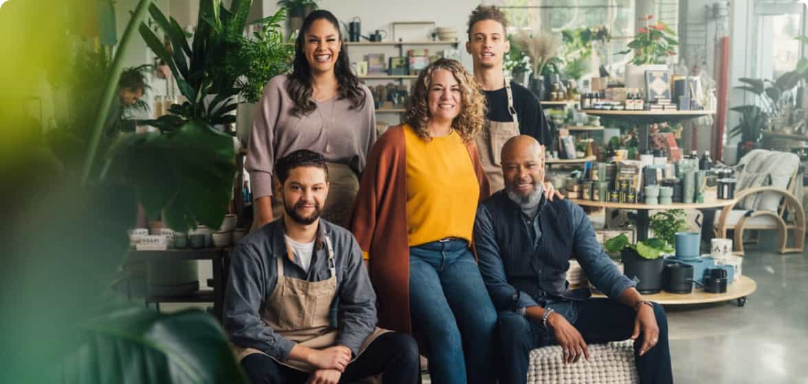 Employees and business owners smiling together for a portrait in their garden shop.
